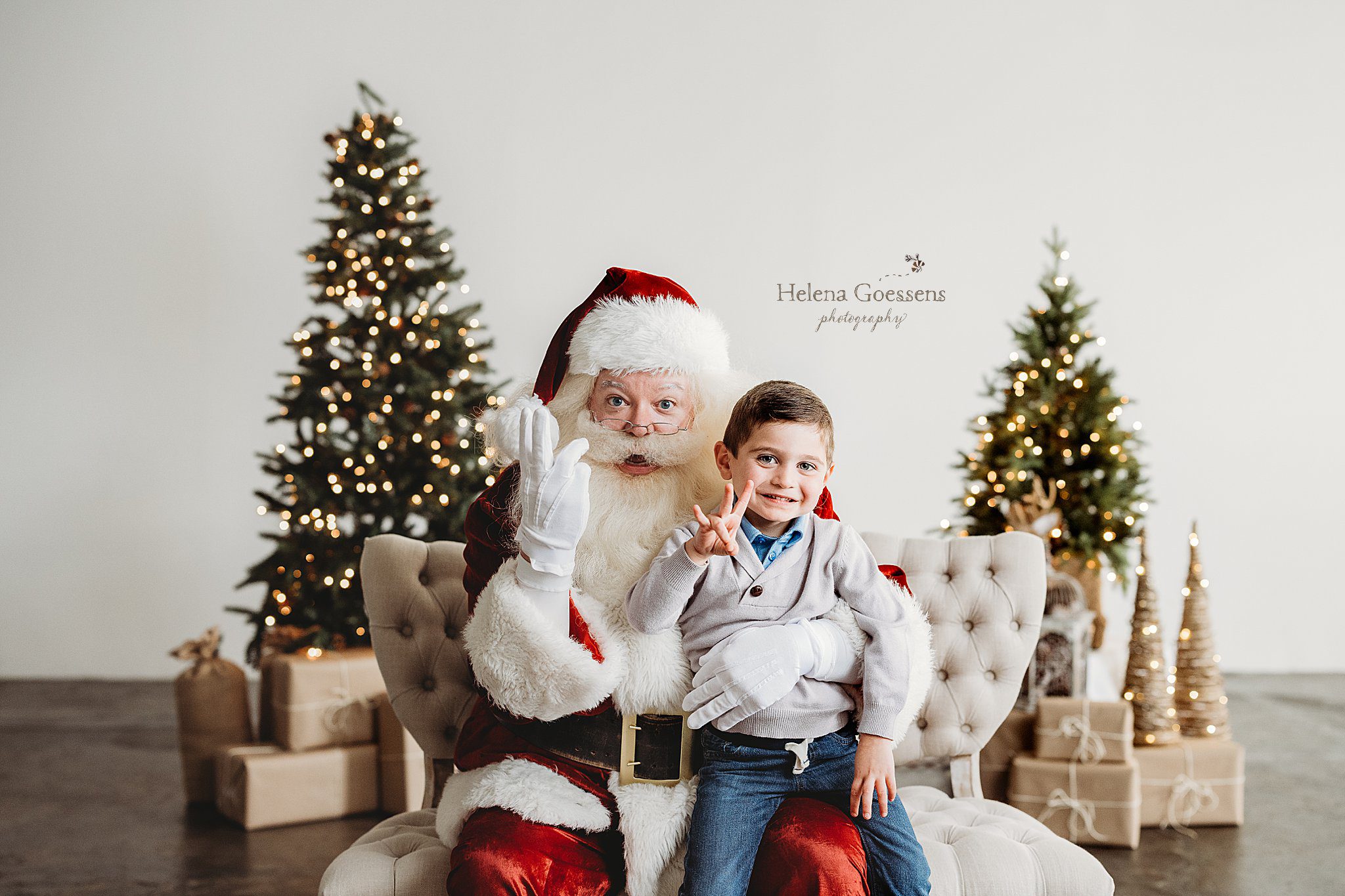 Santa and boy sitting on his lap make reindeer with fingers during Studio Santa Portraits in Norwood, MA