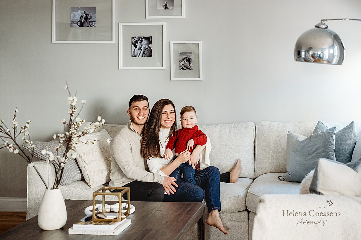 parents sit on couch with son on lap during lifestyle family photos at home in Boston MA
