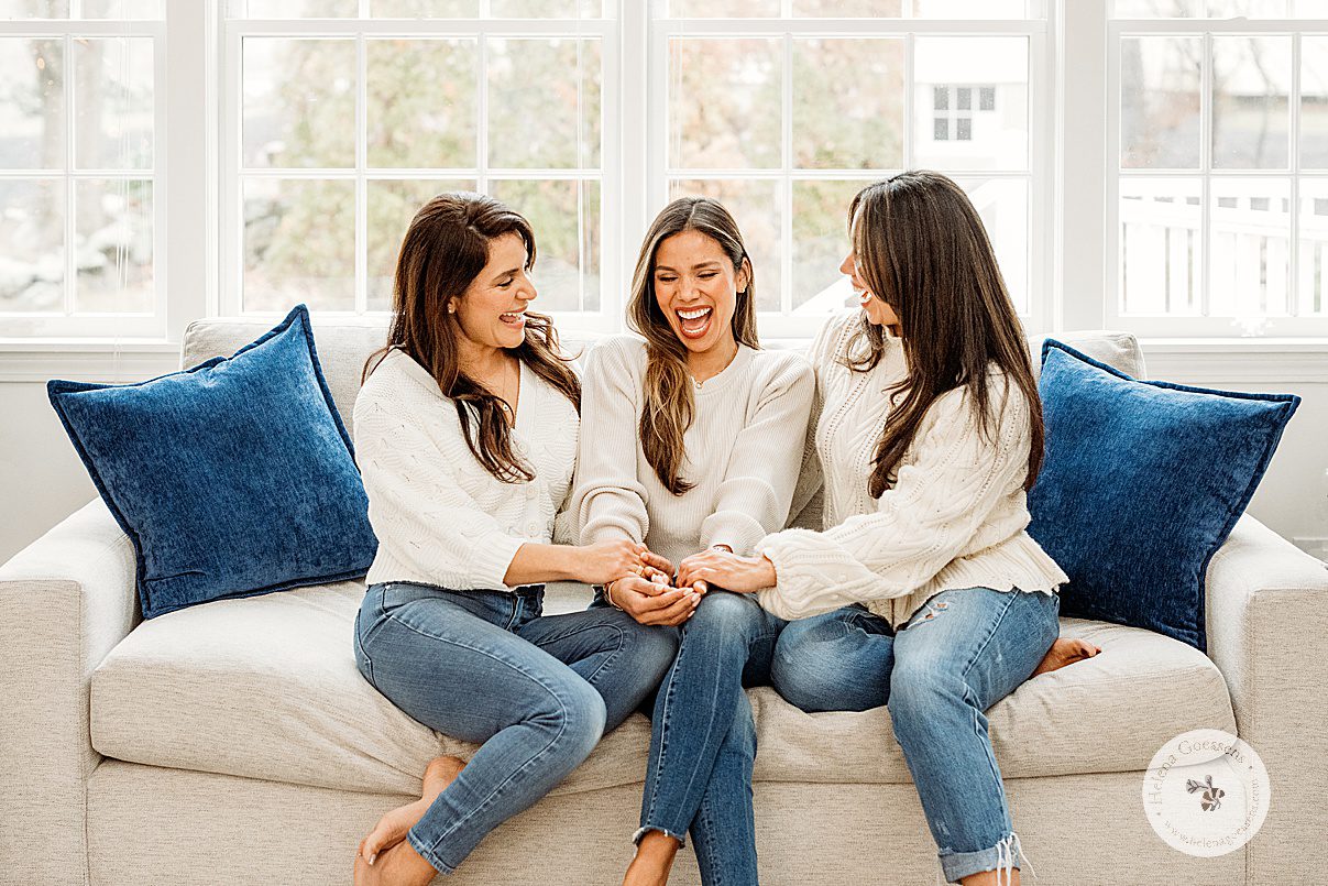 three women laugh sitting on couch together during generational family portraits in Boston MA