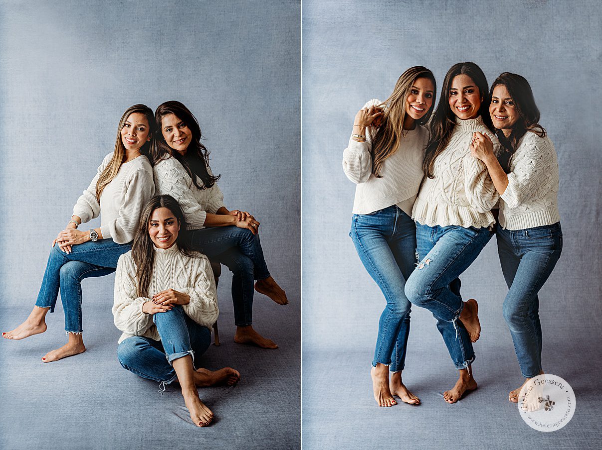 three women hug and pose in cream sweaters on blue backdrop during generational family portraits in Boston MA