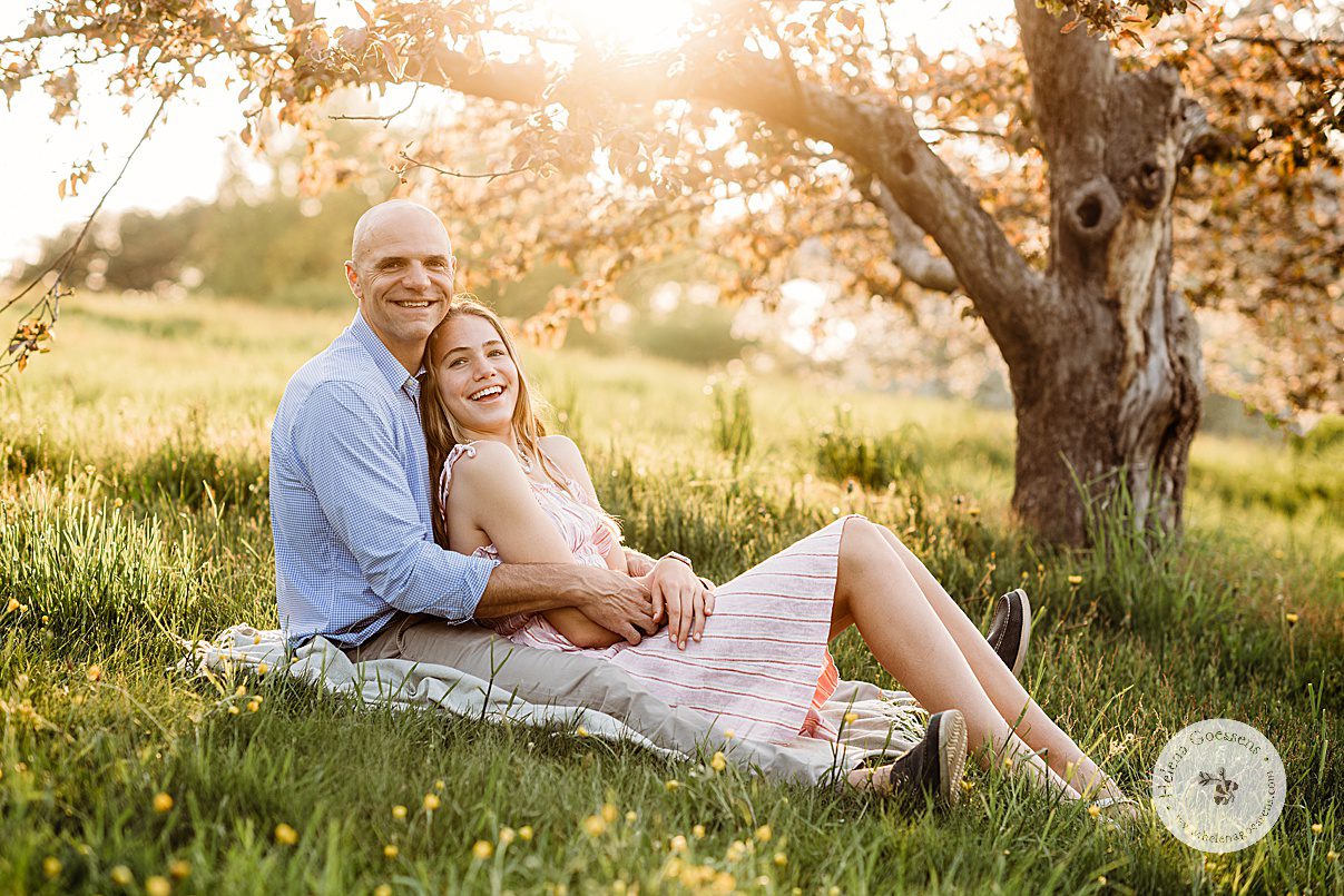 dad holds daughter in between legs on blanket during family photos at Arnold Arboretum