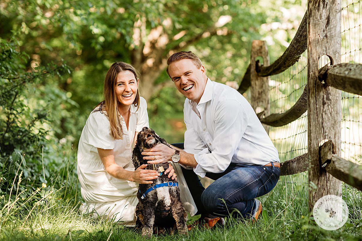 couple kneels with dog near wooden fence during Bradley Estate family photos
