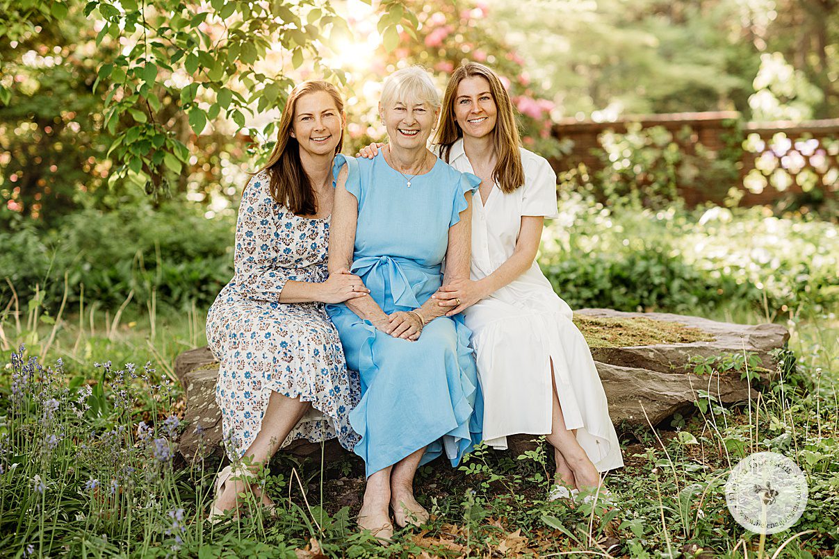 woman in blue dress sits with two daughters in blue and white dresses 