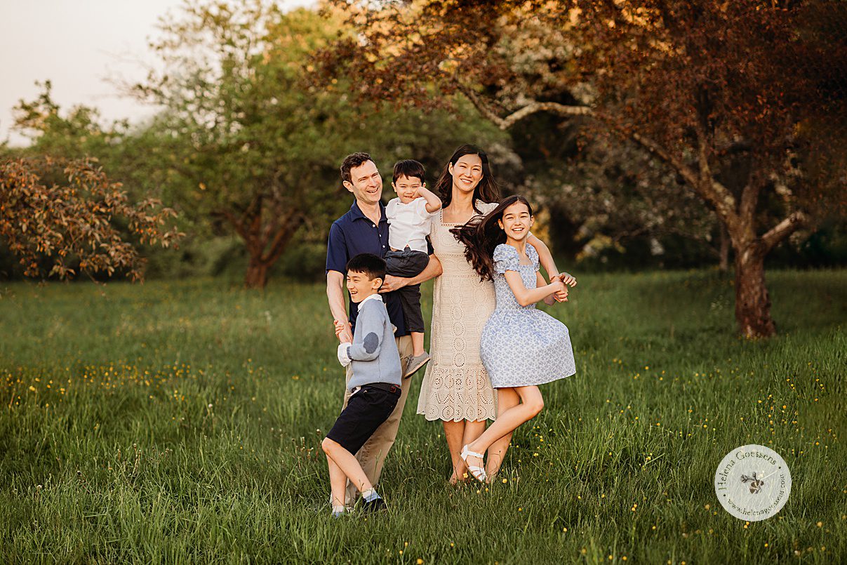 parents walk with three kids at sunset during Arnold Arboretum spring family photos