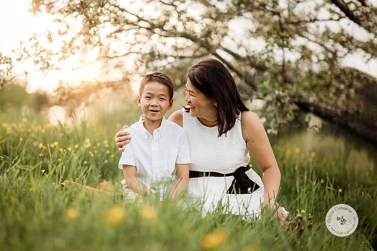 mom laughs with son sitting in grass during Jamaica Plain family portraits at Arnold Arboretum