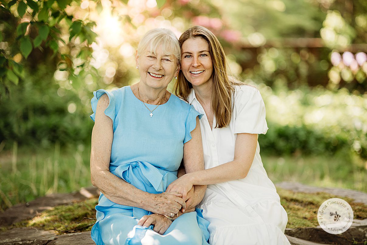 mom in blue dress sits with daughter in white spring linen dress