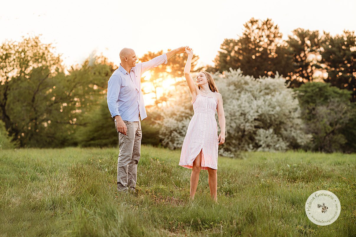 dad twirls daughter under his arm in field during family photos at Arnold Arboretum