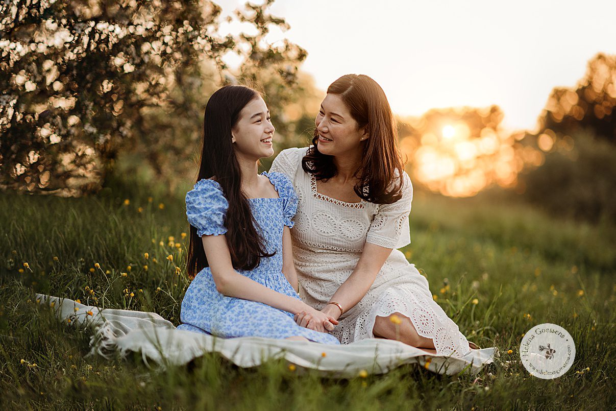 mom sits on blanket with daughter in spring dresses during Arnold Arboretum spring family photos