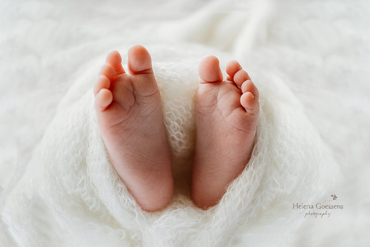 baby's toes poke out of white wrap during lifestyle newborn portraits in Westwood MA