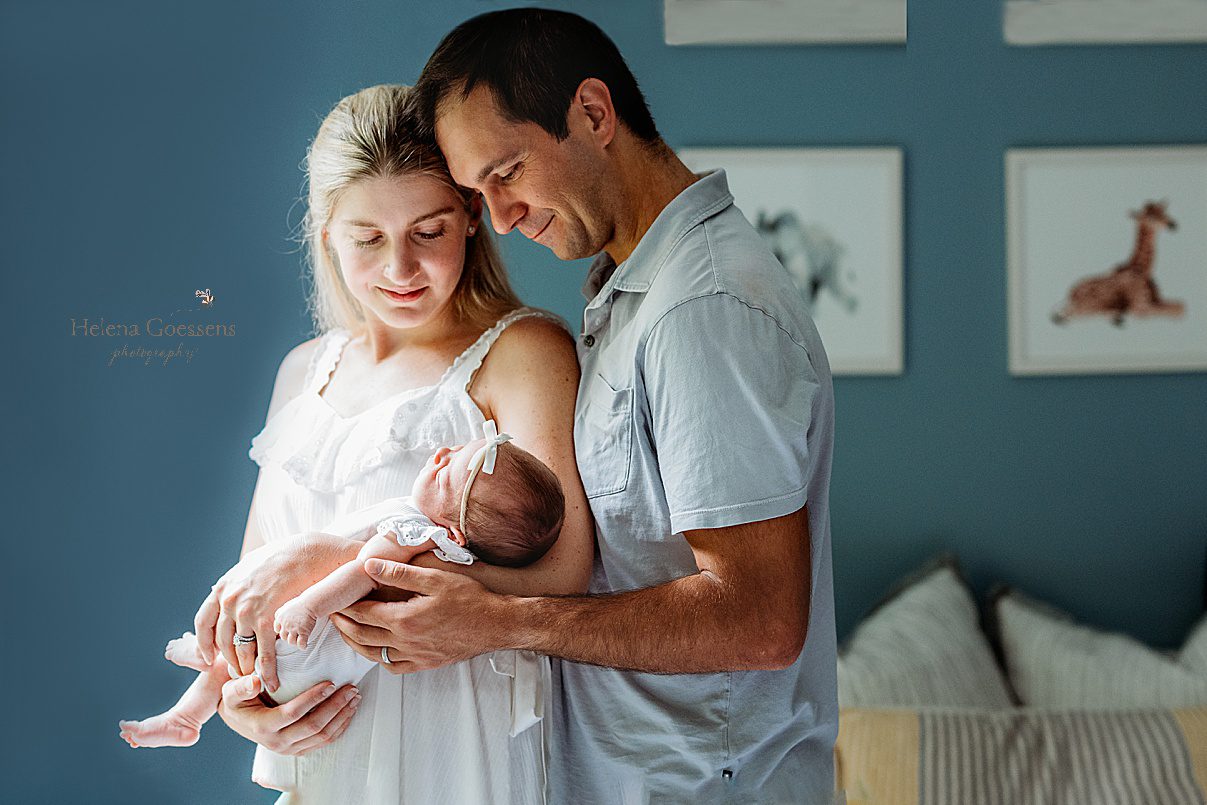 parents hug daughter in front of window during lifestyle newborn photos in Westwood MA