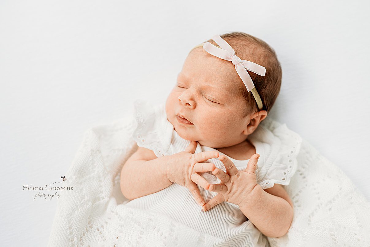 baby sleeps with hands resting together in white blanket with white bow during lifestyle newborn photos in Westwood MA