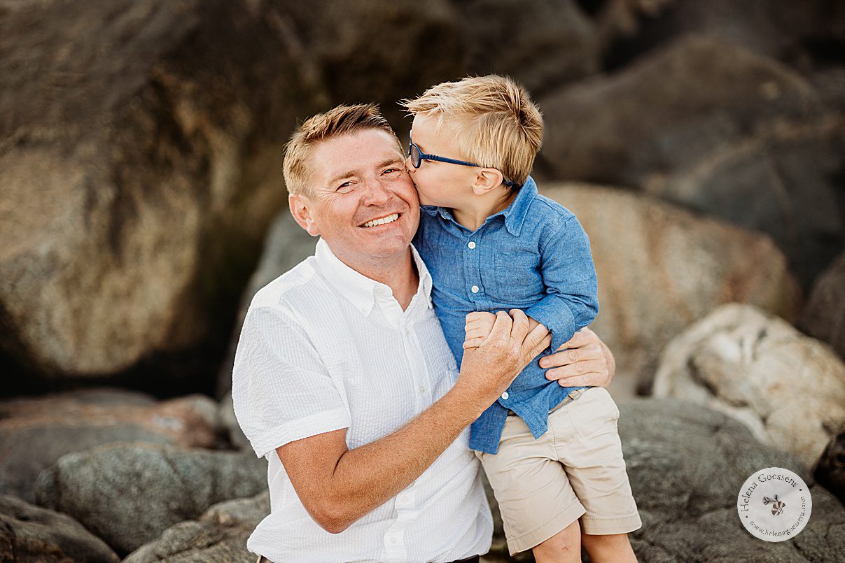 boy in blue button up shirt kisses dad's cheek during summer family photos in Boston MA