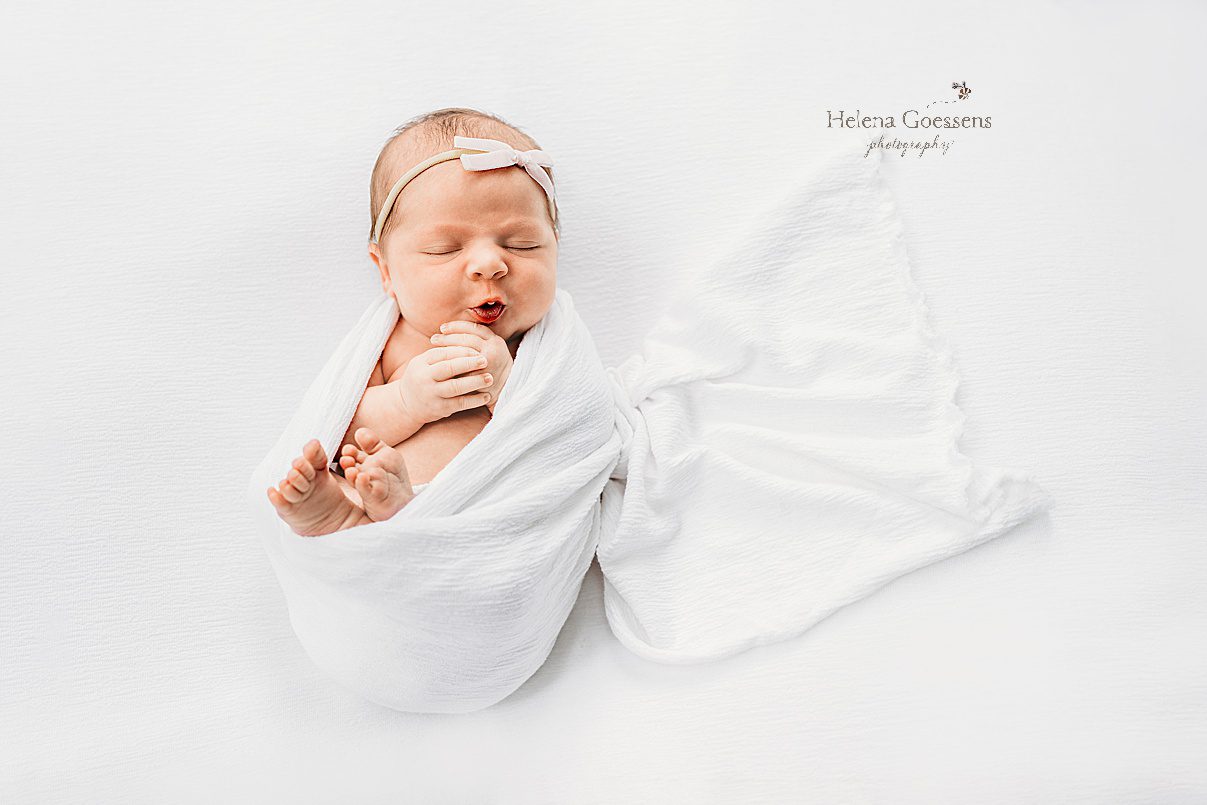 baby girl sleeps in white wrap with small white headband on head during lifestyle newborn photos in Westwood MA