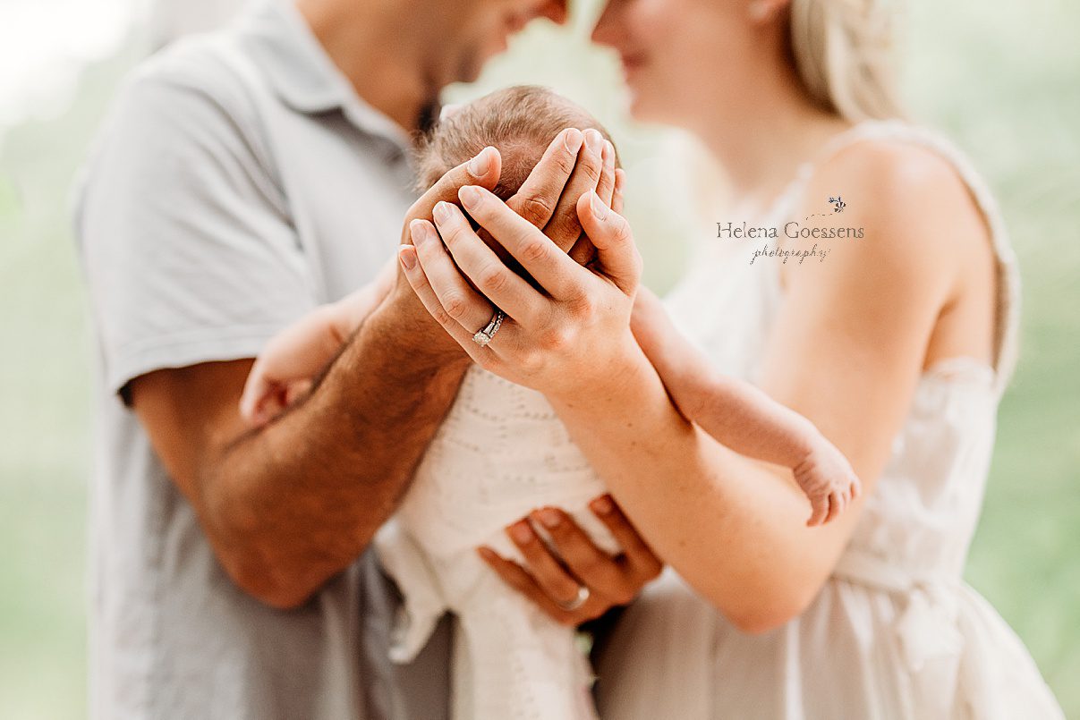 parents hold baby girl while mom holds dad's hand under her head during lifestyle newborn photos in Westwood MA