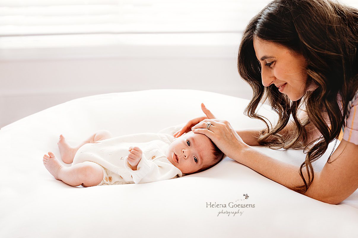 mom rubs son's head smiling at him during lifestyle newborn portraits in Westwood MA