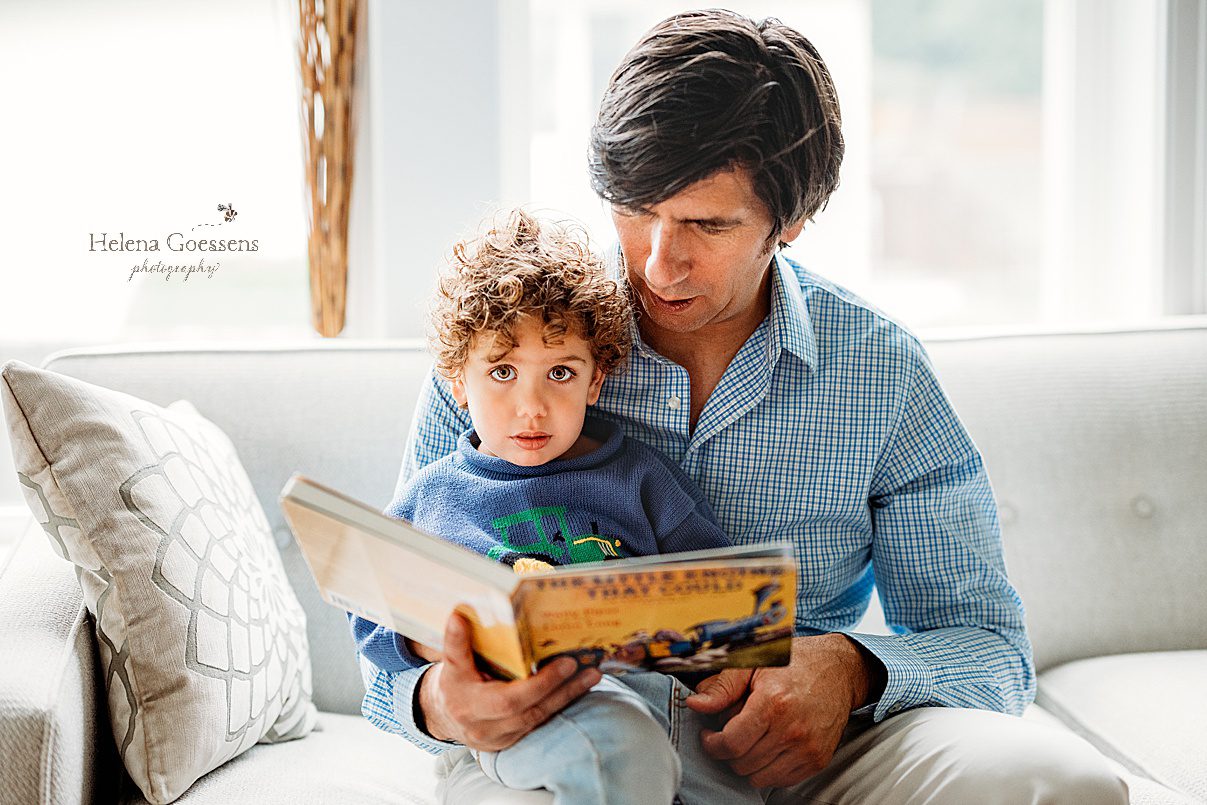 dad sits on couch reading with toddler during Needham MA lifestyle family portraits