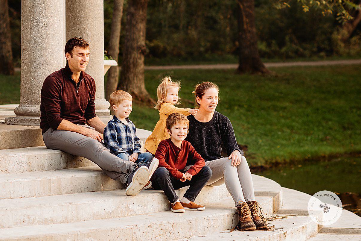 family of five sits on steps inside Larz Anderson Park during fall family portraits