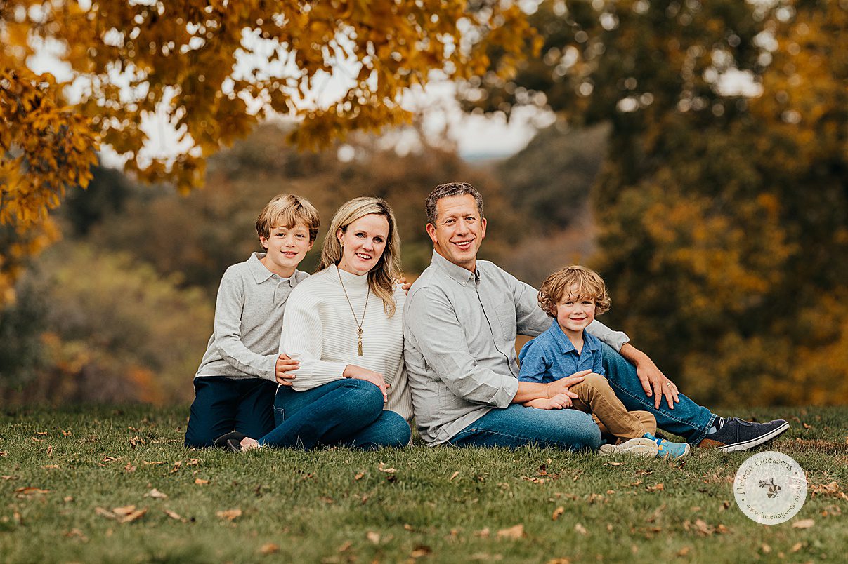 family of four sits together in front of foliage at Larz Anderson Park