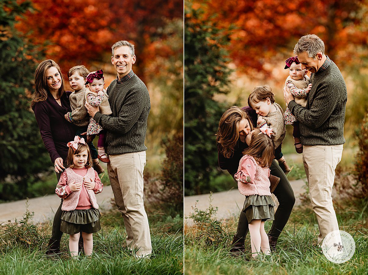 parents hold two children while daughter leans to kiss mom during fall family portraits at Wellesley College