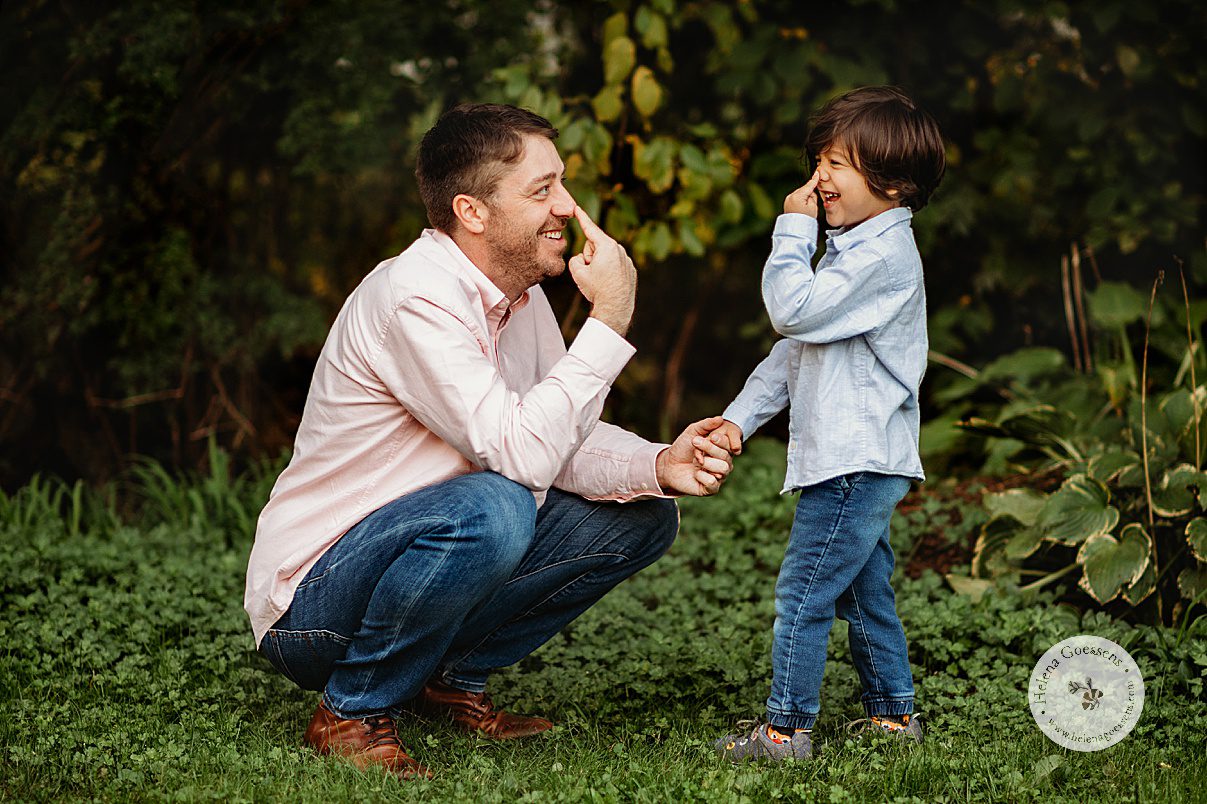 dad and son touch noses during family photos laughing in backyard 