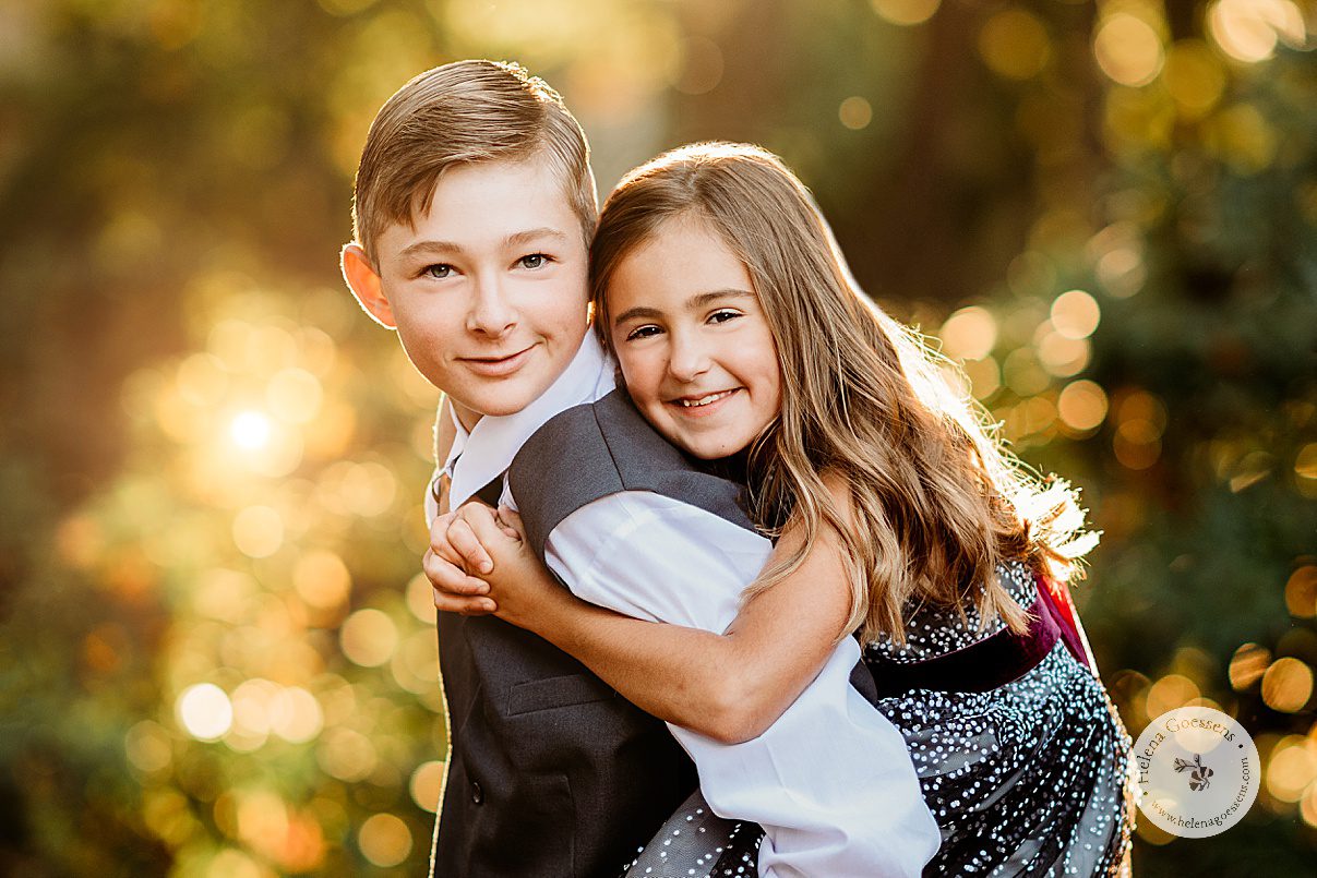 little sister hugs big brother from behind during fall family photos in Boston MA