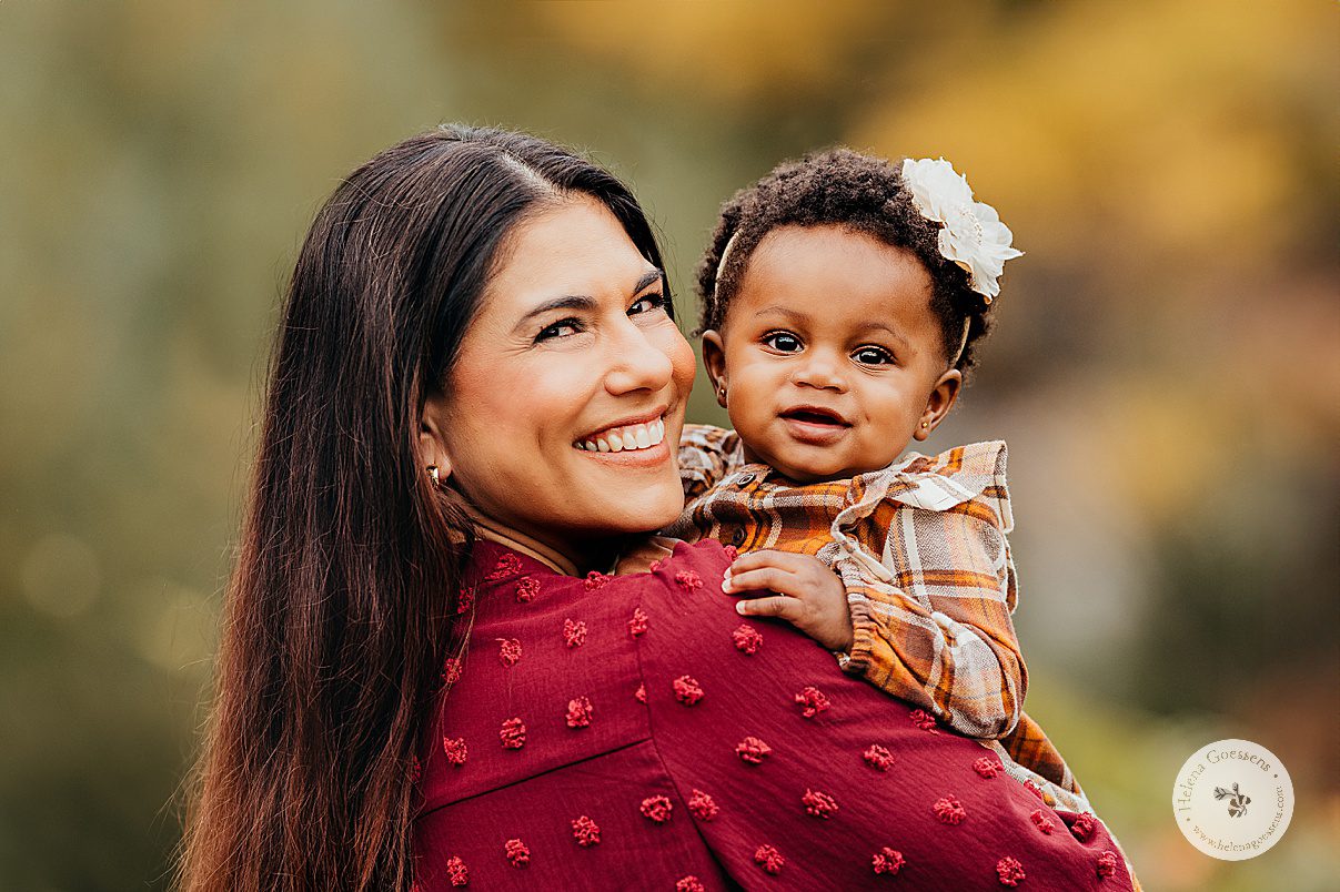mother in burgundy top holds toddler in plaid dress during fall lifestyle family portraits in Westwood MA