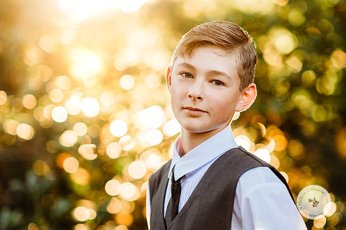 pre-teen boy stands in white shirt and grey vest with black tie during fall family photos 
