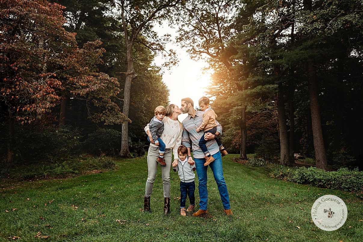 parents hold three sons between them leaning for a kiss during fall family portraits at the Bradley Estate