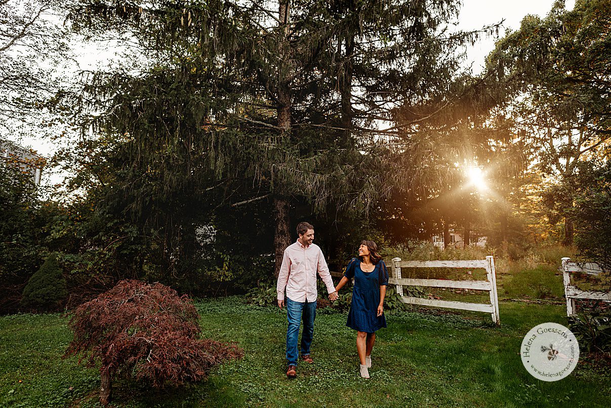 couple holds hands walking through backyard at sunset in Dedham MA