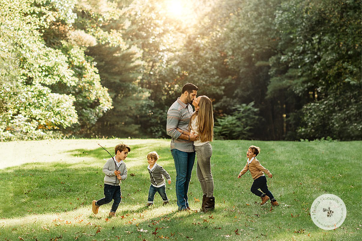 parents kiss while three young boys run around them during fall family portraits at the Bradley Estate