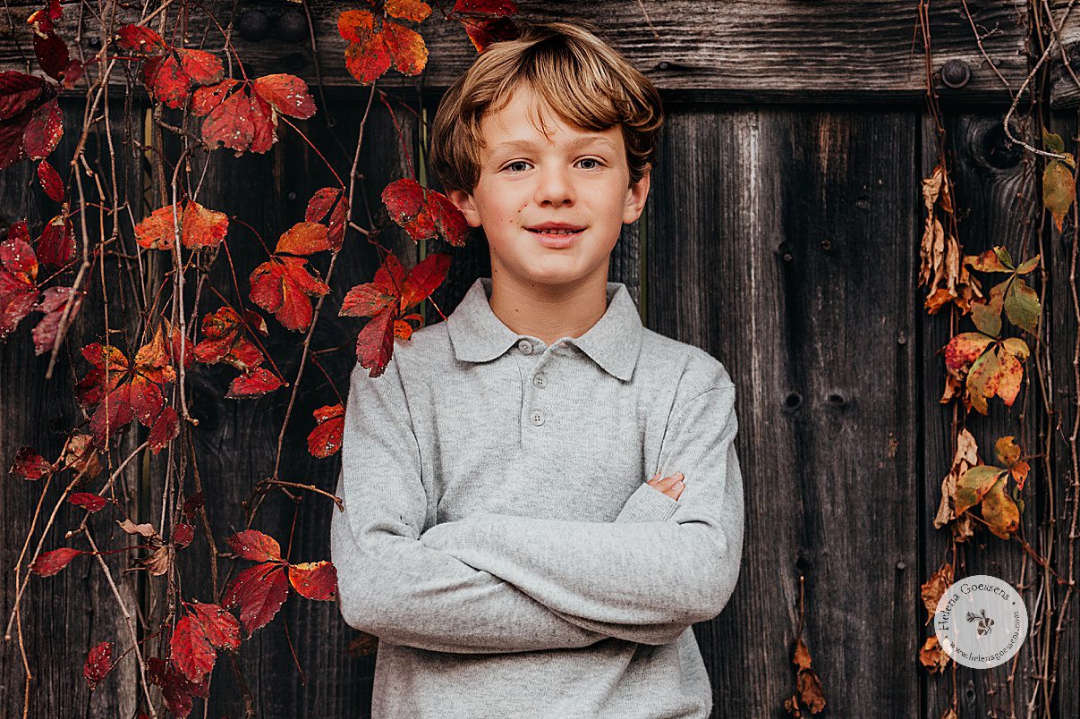 boy in grey shirt stands with arms crossed during fall photos at Larz Anderson Park