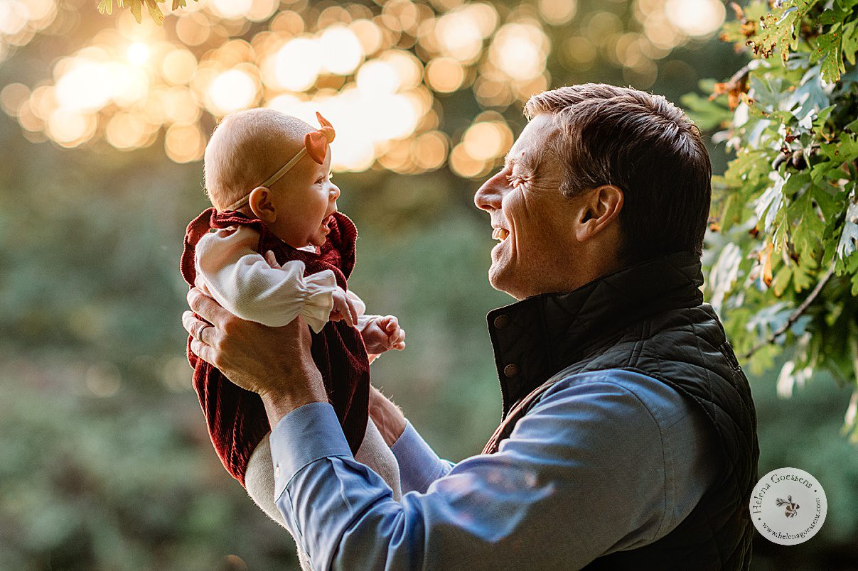 dad holds updated daughter at sunset in leaves at Wellesley College