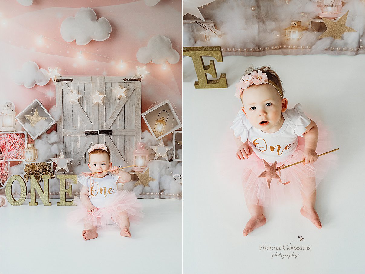 one year old girl sits in front of wooden door with gold and pink decor for first birthday cake smash in Dover MA