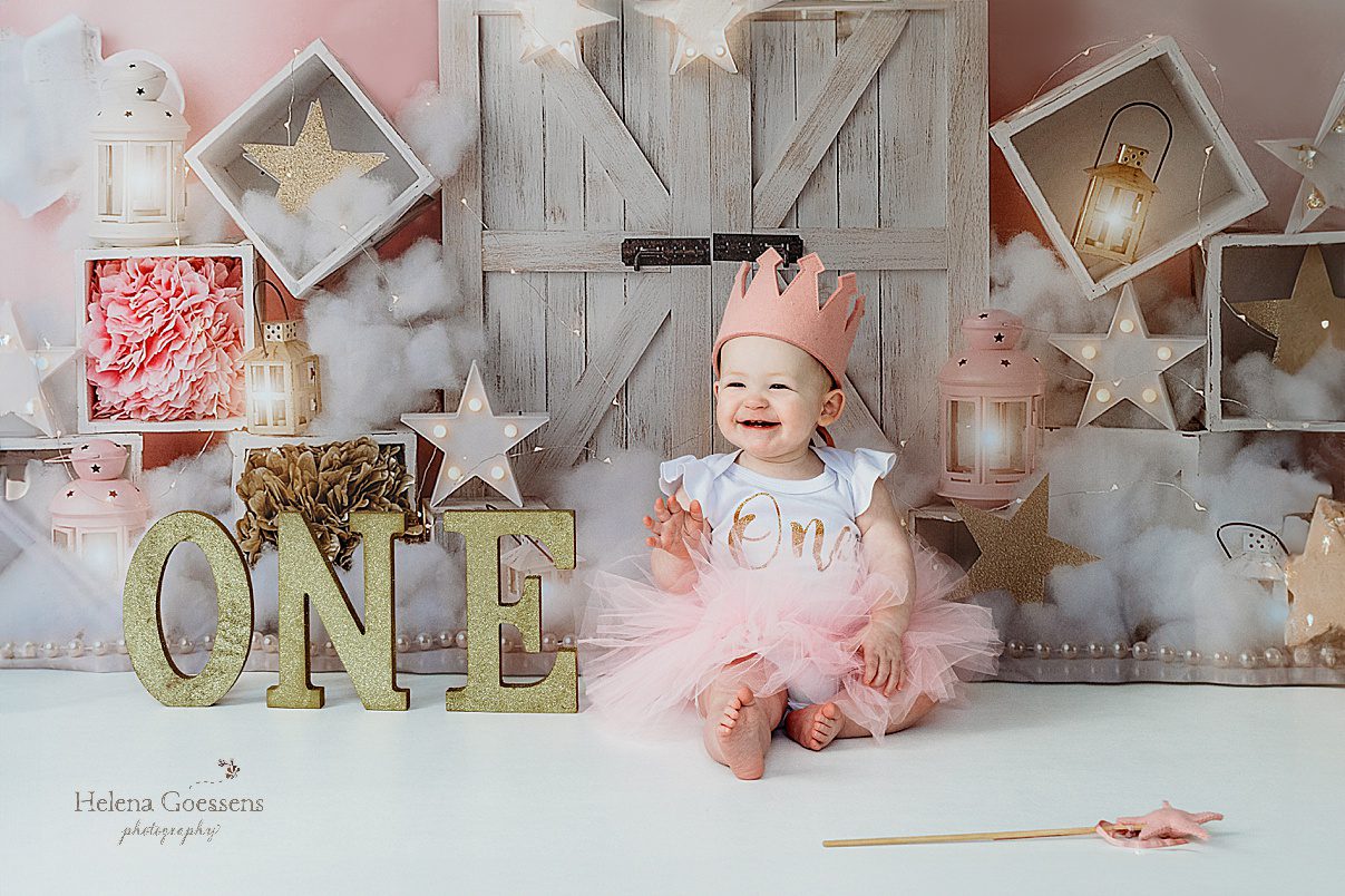 toddler girl laughs wearing pink crown and pink tutu with white and gold ONE shirt during first birthday cake smash in Dover MA