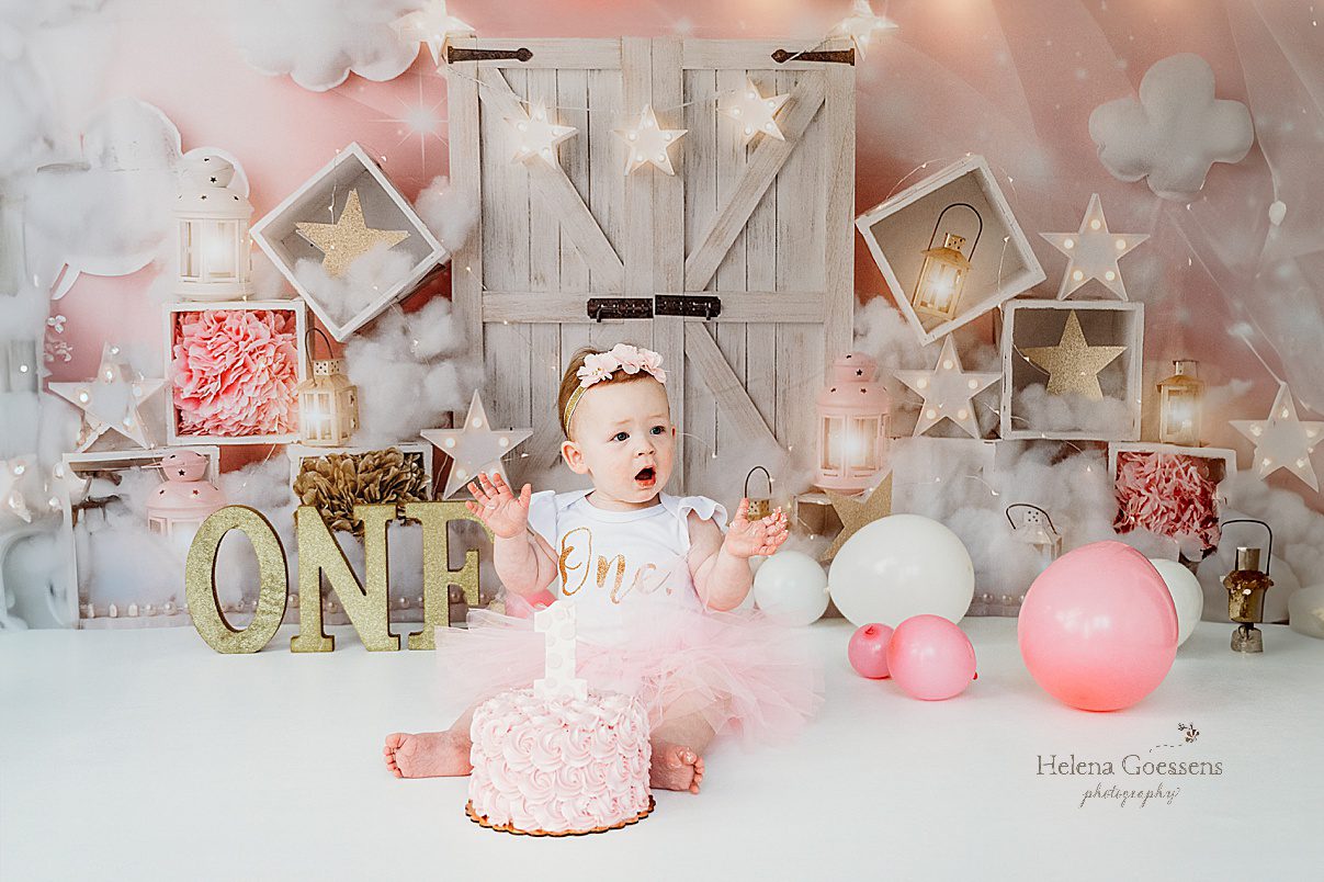 baby smiles sitting behind cake during first birthday Twinkle Twinkle Little Star cake smash with pink, gold, and white details 