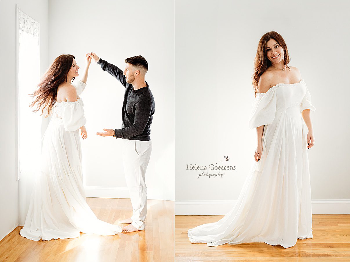 husband twirls wife in front of window in long white gown during portraits at home