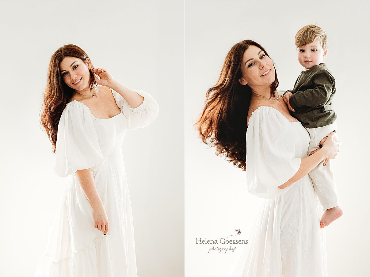 mother in white dress lifts up toddler son turning head so hair floats 