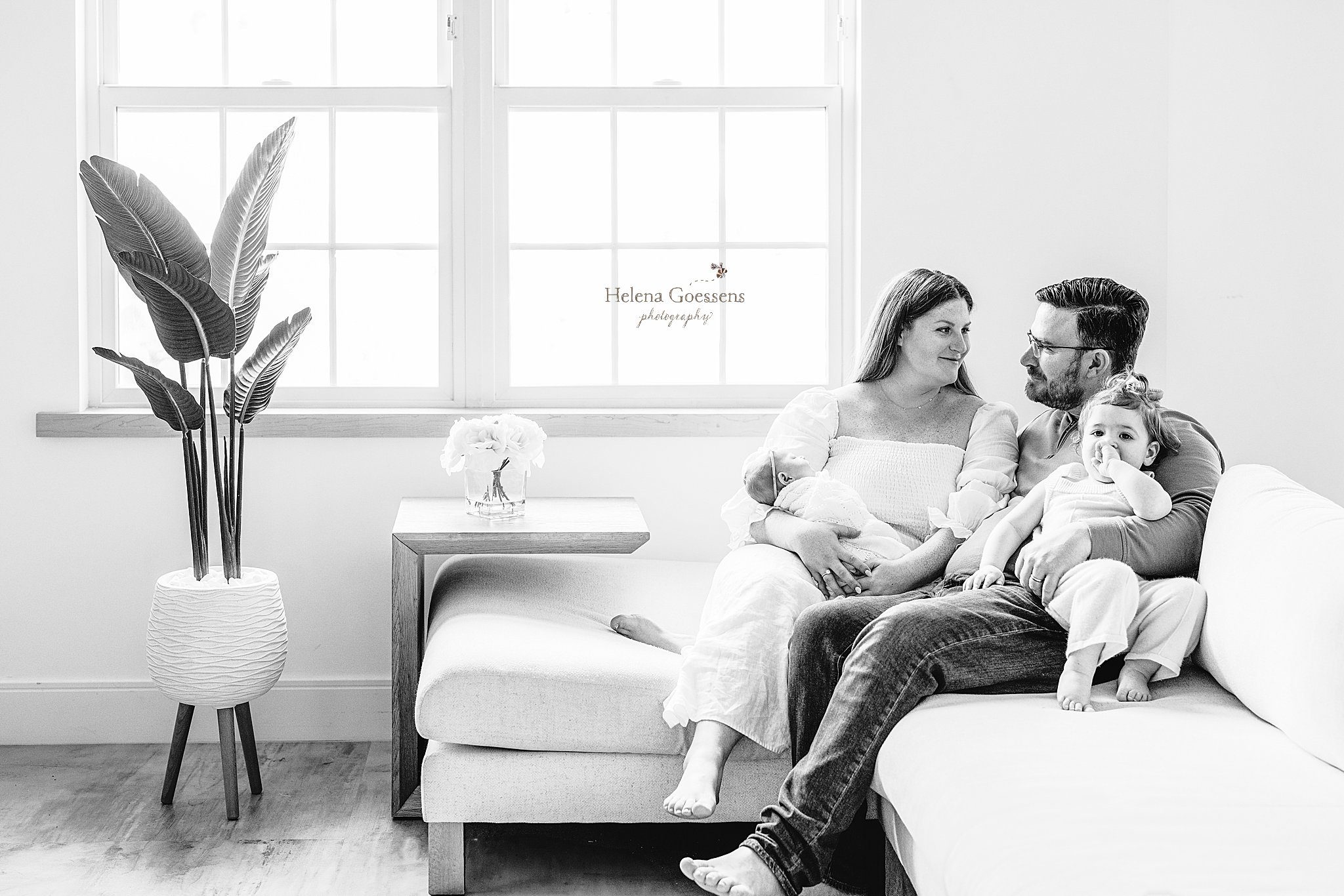 family of four sits on couch during at home newborn portraits in Canton MA