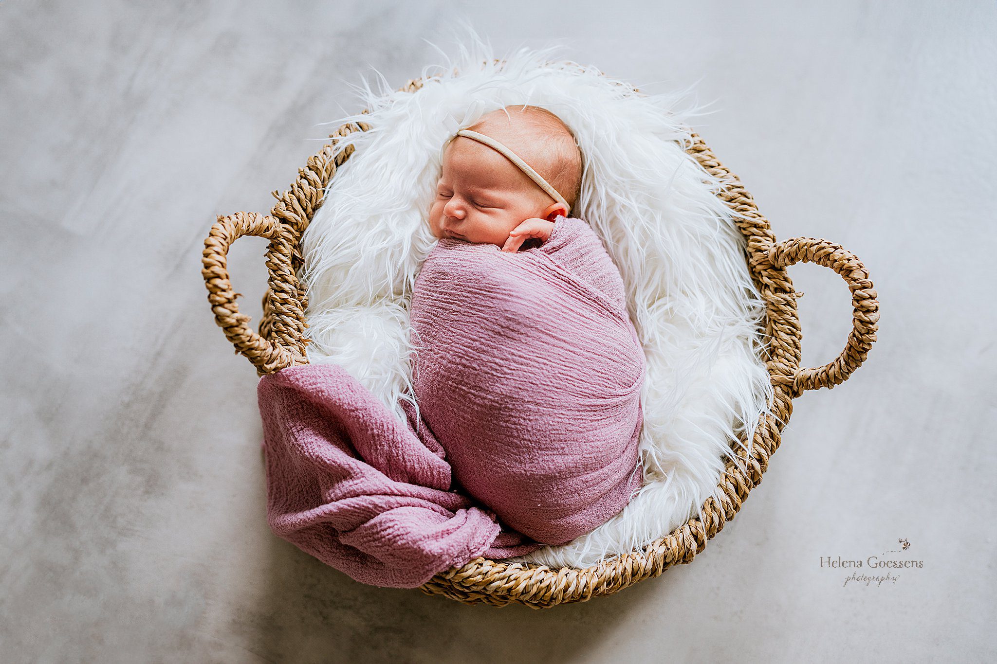 baby lays in basket in pink wrap with white fluffy blanket during at home newborn portraits in Canton MA