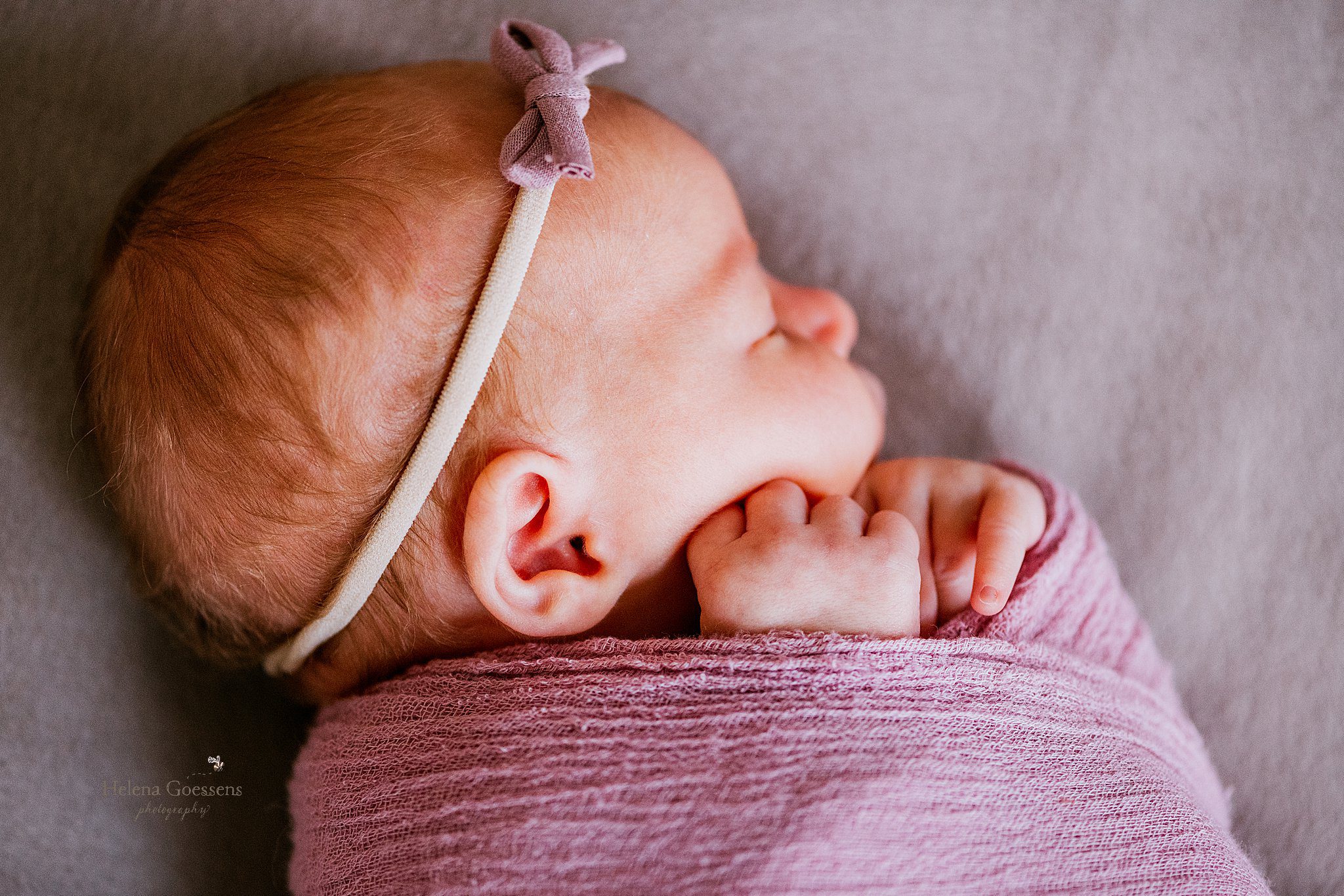 baby girl lays in pink wrap with matching bow during newborn portraits at home 