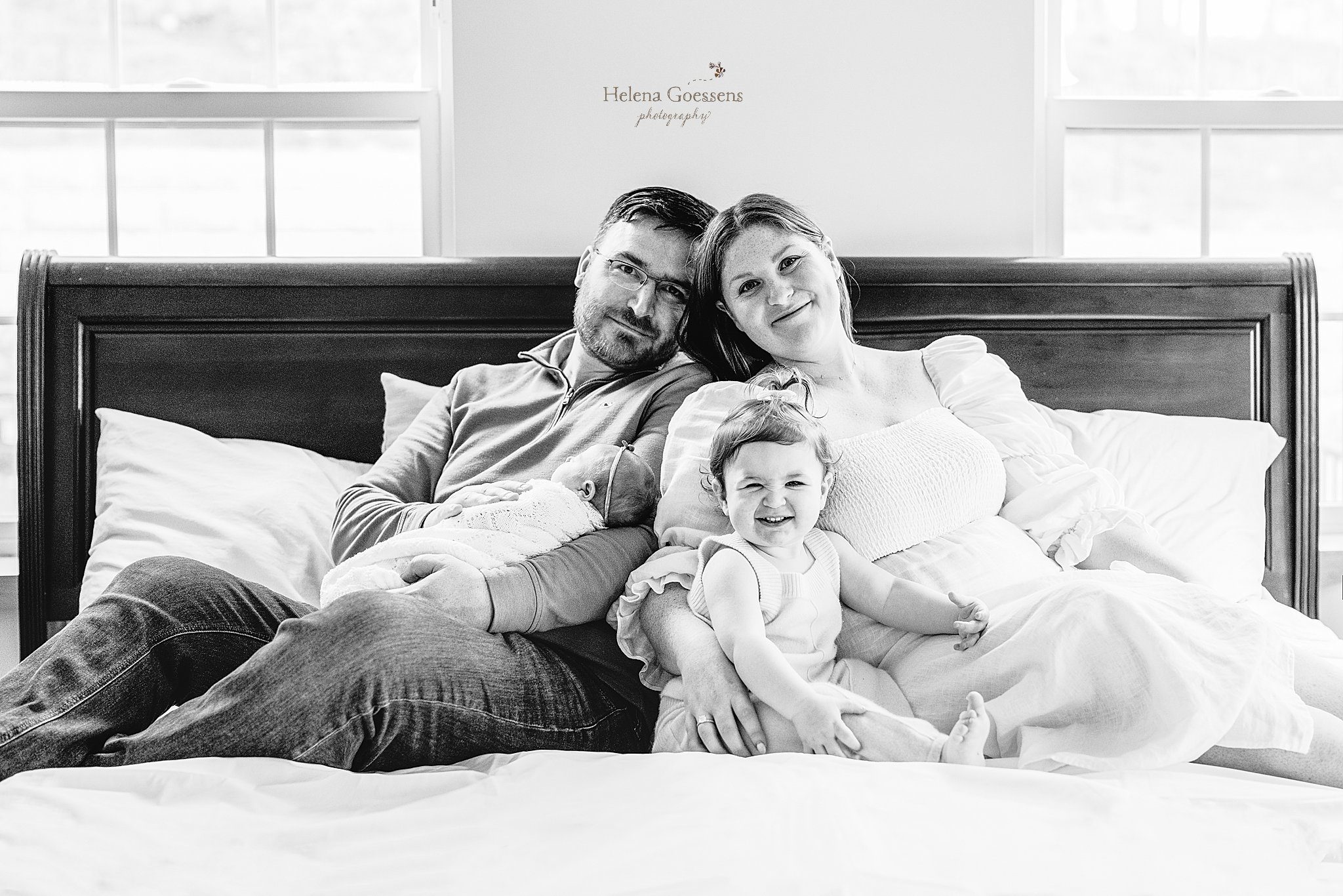 family of four snuggles on bed during at home newborn portraits in Canton MA
